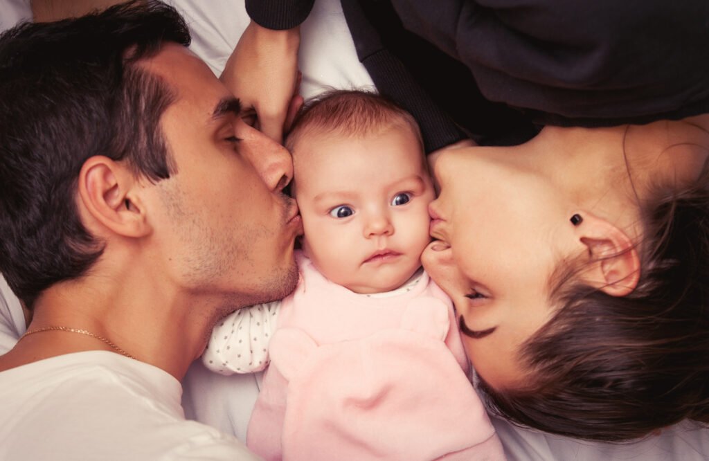 Ein Paar verbringt einen zärtlichen Moment mit seinem Baby auf einem Bett.